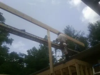 Carpenter setting a ridge beam over a new addition frame — Ice Dam Removal by Roofing Brothers in Fall Branch