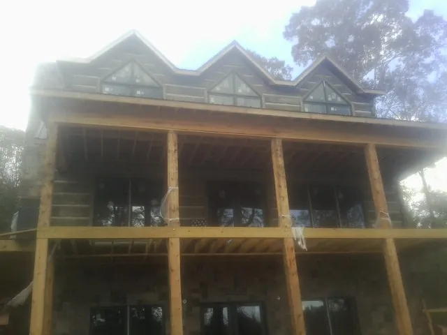 Dormers and porch framing on a large log home under construction — Roof Coating work by our crew in Fall Branch