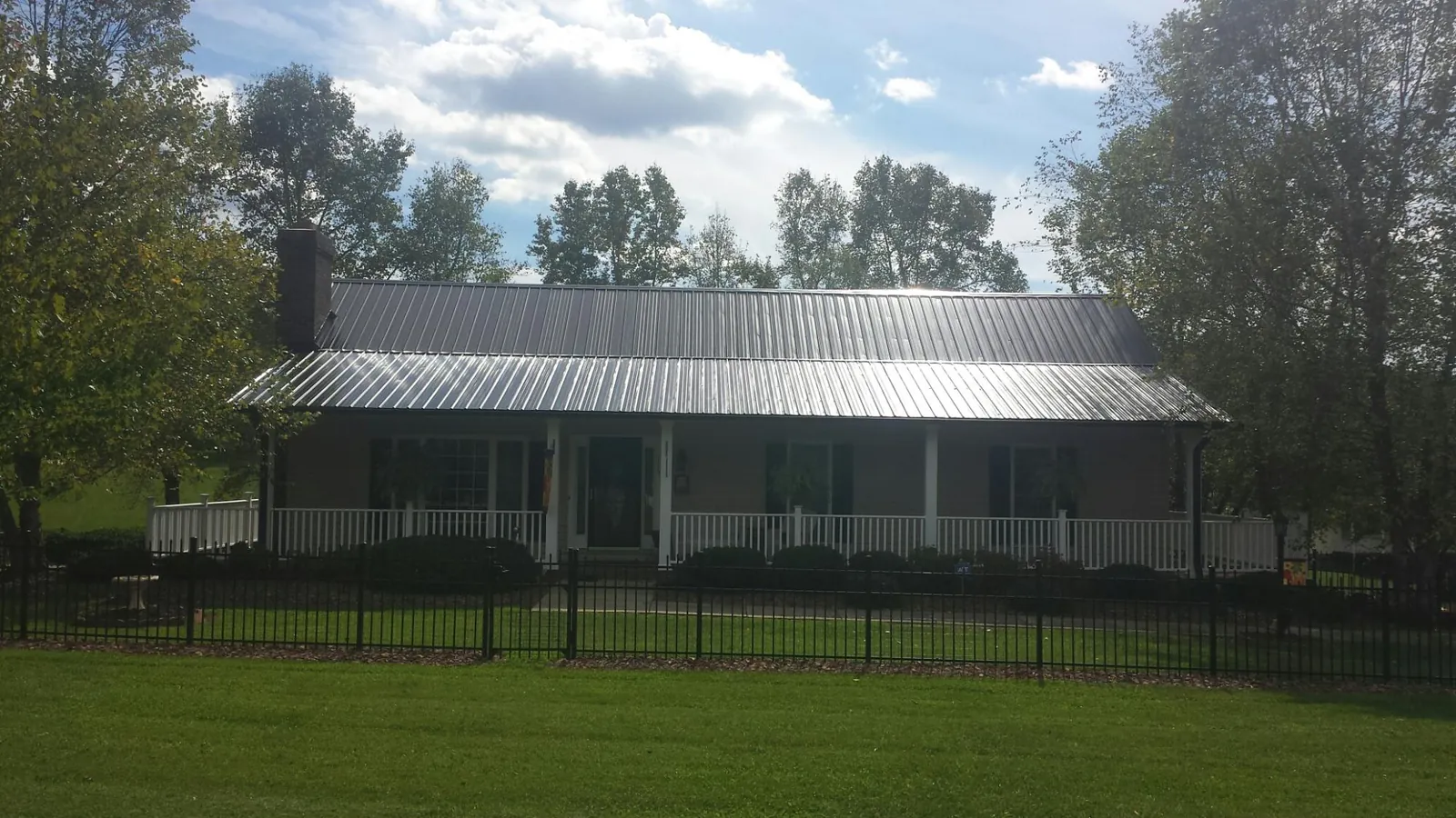 Gray metal roof on a brick ranch with a full width front porch — Gutter Guard Installation work by our crew in Fall Branch