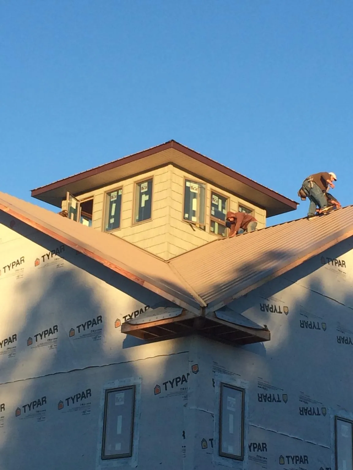 Roofers working around a rooftop cupola on a new metal roof at sunset — Roof Waterproofing in Fall Branch by Roofing Brothers